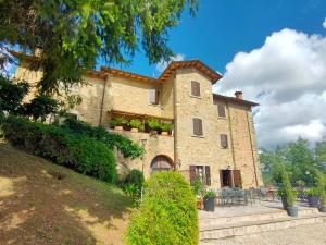 a large stone building with plants on the windows at Agriturismo L'Essiccatoio in Lisciano Niccone