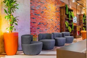 a group of stools in a room with a brick wall at Linked Batel Curitiba by Xtay in Curitiba +68 photos