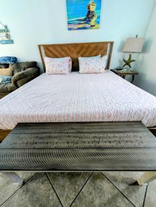 a large bed with a bench in a bedroom at Steps to Beach & Downtown Fun in Cocoa Beach