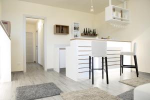 a white kitchen with a counter and two stools at La Giara in Marina di Modica