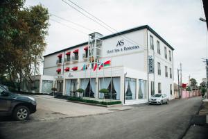 a white building with a car parked in front of it at AS Hotel Ganja in Ganja