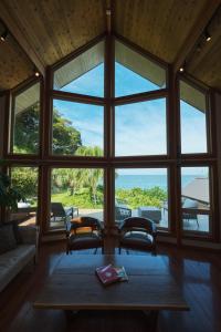 a living room with a large window with a table and chairs at Monterey House by SANA in Tateyama