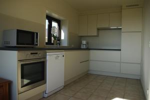 uma cozinha com armários brancos, um micro-ondas e um fogão em Gîte Horlitin em Amougies