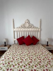 a white bed with red pillows in a bedroom at Casa Clementina in Albufeira