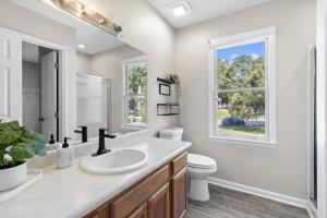 Un baño con lavabo, inodoro y ventana. en Cozy Home Away from Home- 10MIN From DT Durham, en Durham 18 fotos más