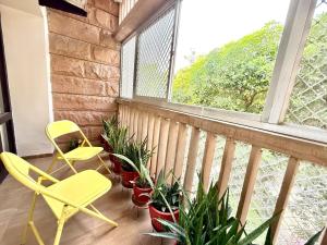 Un balcón con dos sillas y plantas y una ventana. en Marwar Essence, en Jodhpur