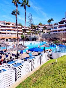 einen Pool mit Stühlen und Sonnenschirmen in einem Resort in der Unterkunft Appartamento Parque Albatros vista piscina e mare in San Miguel de Abona + 30 Fotos