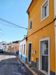 a street in an old town with colorful buildings at Yellow House in Tavira