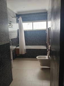 a bathroom with a toilet and a tub and a sink at Hotel bougainvillea Victoria island in Lagos
