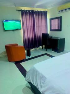 a bedroom with a bed and a desk and a computer at Hotel bougainvillea Victoria island in Lagos +11 photos