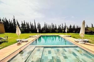 a swimming pool with chairs and umbrellas in a yard at Dar hamama - Villa familiale - Marrakech in El Aggada