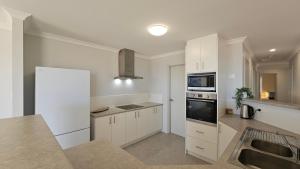 eine Küche mit weißen Schränken und einer Spüle in der Unterkunft Pelican Shore Villa 3A- Kalbarri, WA in Kalbarri