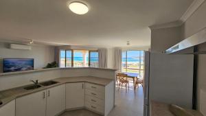eine Küche mit weißen Schränken und einem Tisch mit Meerblick in der Unterkunft Pelican Shore Villa 3A- Kalbarri, WA in Kalbarri