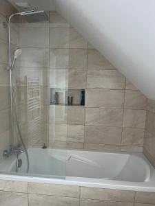 a bathroom with a bath tub with a shower at Charmant corps de ferme - Proche de la mer in Plougonvelin
