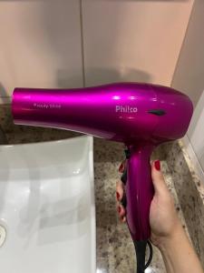 uma pessoa está segurando um secador de cabelo roxo em todo climatizado, 2 quartos e piscina na 706 sul em Palmas mais 20 fotografias