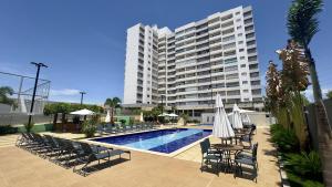 a hotel with a pool and chairs and a large building at Apartamentos Recanto do Bosque in Caldas Novas