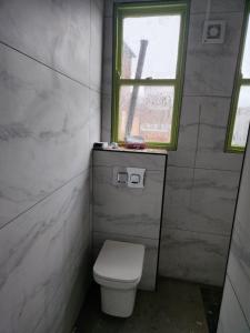 a small bathroom with a toilet and a window at Main Wasall High Street flat above shop in Walsall