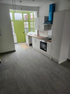 an empty kitchen with white cabinets and a green door at Main Wasall High Street flat above shop in Walsall