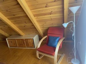 a red chair with a blue pillow in a attic at Eiross Apartmanház in Tamási