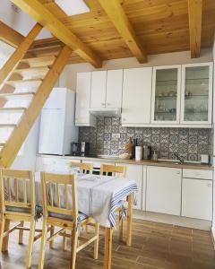 a kitchen with white cabinets and a table and chairs at Eiross Apartmanház in Tamási