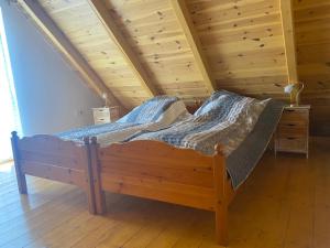 a wooden bed in a room with a wooden ceiling at Eiross Apartmanház in Tamási
