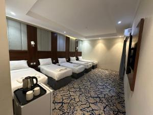a row of beds in a hotel room at Manasik Al Bait Hotel Makkah in Makkah