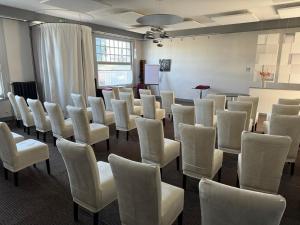 ein Raum voller weißer Stühle und eines Podiums in der Unterkunft Cit'Hotel Capricorne in Vendôme