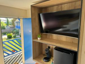 ein großer Flachbildfernseher auf einem hölzernen Entertainment-Center in der Unterkunft Cit'Hotel Capricorne in Vendôme