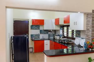 una cucina con armadi rossi e bianchi e un frigorifero nero di CLUB 4 Homestay a Nedumbassery