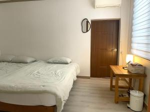 a bedroom with a bed and a table and a door at Danaharu Guesthouse in Jeonju