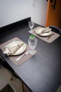 a table with two plates and wine glasses on it at 305-1 · Suíte Completa Próx Ânima/Cebrom 305 in Anápolis