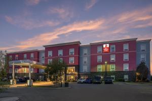 a large red building with cars parked in a parking lot at Best Western Plus Airport Inn & Suites in Saskatoon