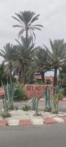a sign in front of palm trees in a street at Atlas Golf Resort - Marrakech in El Mgassem