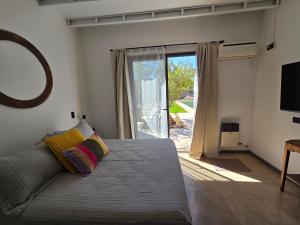 ein Schlafzimmer mit einem Bett und einer Glasschiebetür in der Unterkunft Patio Jarilla in El Challao
