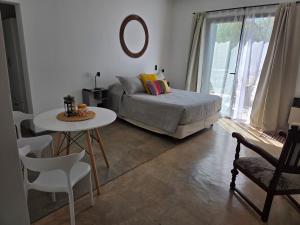 ein Schlafzimmer mit einem Bett, einem Tisch und einem Stuhl in der Unterkunft Patio Jarilla in El Challao