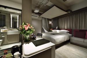 una camera con letto e scrivania con vaso di fiori di Xi Hotel a Hong Kong