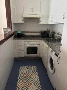 a kitchen with white cabinets and a washer at Beautiful apartment next to the historic center in Vigo