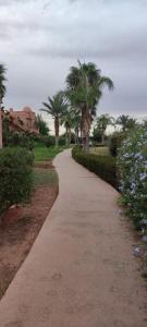 a walking path in a park with palm trees at Atlas Golf Resort - Marrakech in El Mgassem +11 photos