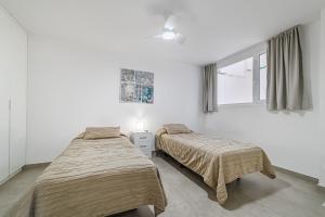 zwei Betten in einem weißen Zimmer mit Fenster in der Unterkunft Magnífico Bungalow con Vista Panorámica y Piscina Privada in Acantilado de los Gigantes + 31 Fotos
