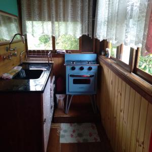 a small kitchen with a stove and a sink at Pau a Pique Chalé in Bocaina de Minas