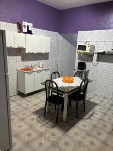 eine Küche mit einem Tisch mit Stühlen und einer Mikrowelle in der Unterkunft Casa da Dona Vera in Olímpia