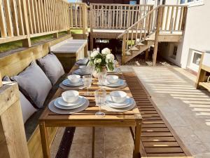 a wooden table with plates and cups on a patio at The Light Keepers Retreat in Cromer
