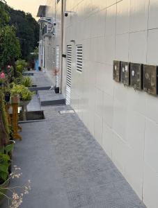 an empty alley with a white wall and some plants at Cantinho Aconchegante - Quarto com Ar-cond 3 in Bayeux