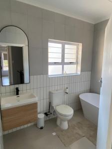 a bathroom with a toilet and a tub and a sink at 4 La Toinette in Ballito