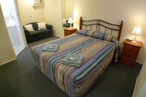 Un dormitorio con una cama con dos bolsas. en Parkhaven Motel en Goulburn