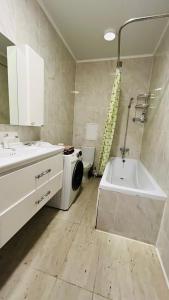 une salle de bain avec un lavabo et une machine à laver dans l'établissement ЖК Асель, à Atyraū