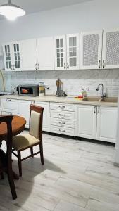 une cuisine avec des armoires blanches et une table et des chaises dans l'établissement ЖК Асель, à Atyraū 2 autres photos