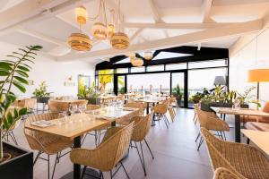 a restaurant with tables and chairs and windows at Hôtel L'Albatros in Saint-Trojan-les-Bains