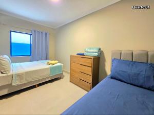 a bedroom with two beds and a dresser and a window at Apt novo a poucos passos do mar em Meia Praia Itapema 2 quartos in Itapema
