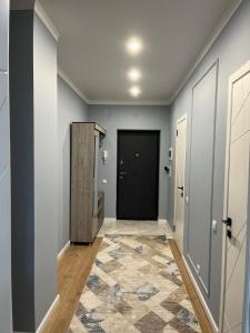 a hallway with a black door and a rug at Комфортные апартаменты в ЖК Наурыз парк in Shymkent